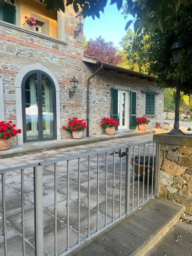 a fence in front of a building with red flowers at Appartamento in villa - Maria Grazia in Scarperia