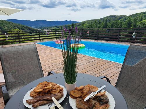 a table with a plate of food on it with a pool at Kuća za odmor MARE in Lepoglava