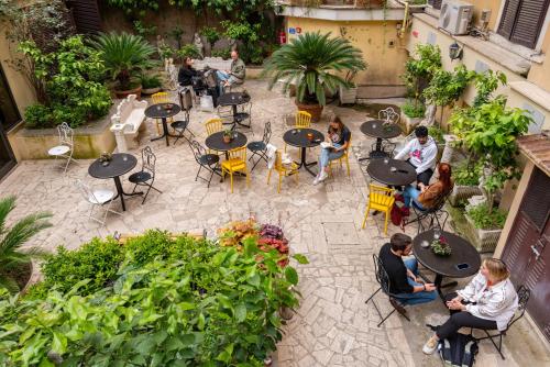 a group of people sitting at tables in a garden at Ostello Bello Roma Colosseo in Rome