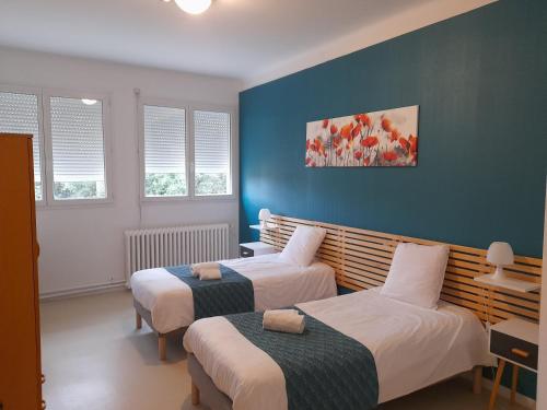 two beds in a room with blue walls and windows at Centre Louis Ormières in Montauban