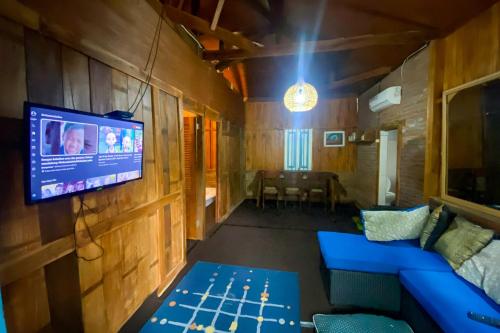 a living room with a tv and a blue couch at Lembah Mbalong Resort Mitra RedDoorz Near Exit Tol Singosari in Blimbing