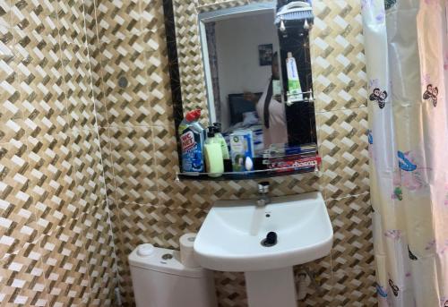 a bathroom with a sink and a mirror over a toilet at Villa de chez nous in North Legon