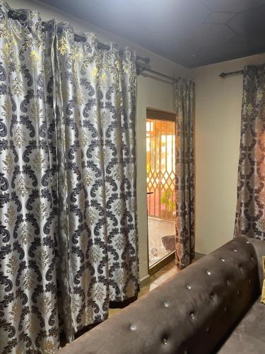 a bedroom with curtains and a bed and a window at Villa de chez nous in North Legon