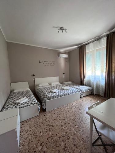 a room with three beds and a table and a window at ViaVai Pisa Airport in Pisa