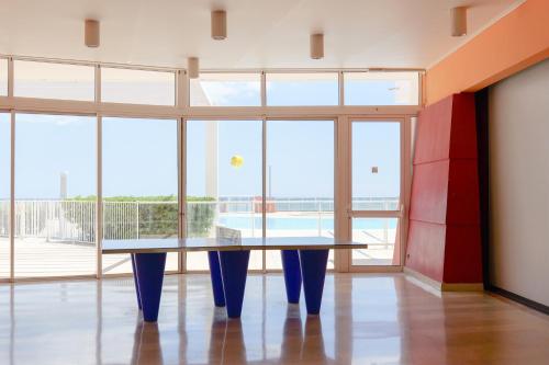 une table au milieu d'une pièce avec de grandes fenêtres dans l'établissement Appartement C 529 piscine front de mer, à Sète