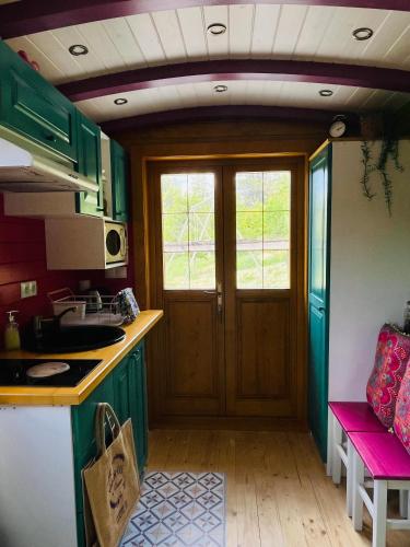 - une cuisine avec des placards verts et une porte en bois dans l'établissement Roulotte Bohème en Provence, Terra Luna, Valensole, à Valensole