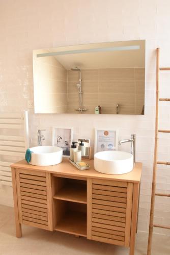 deux lavabos sur un comptoir en bois dans une salle de bain dans l'établissement Secret de la Corniche, à La Reuille