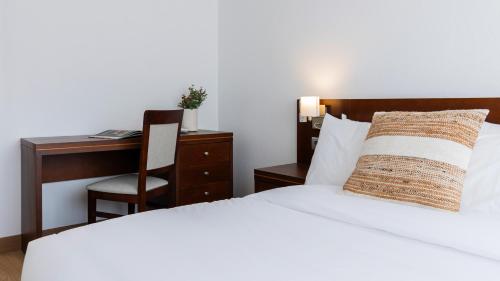 a bedroom with a bed and a desk and a chair at Albergaria Quim Barreiros in Vila Praia de Âncora