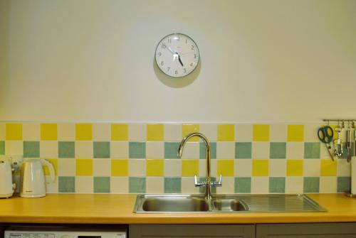 eine Uhr an einer Wand über einer Küchenspüle in der Unterkunft 2a Rose St- cosy coastal cottage Fife in Saint Monance