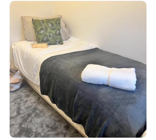 a bed with a black blanket and pillows on it at The Hideout in Trearddur