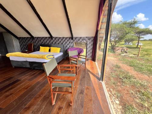 Habitación con cama y sillas en una tienda de safari en Kilimanjaro view cabin-Amboseli, en Oloitokitok 