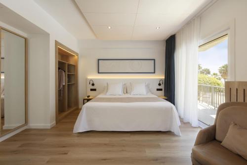 Hotel Rovira في كامبريلس: غرفة نوم بسرير ابيض واريكة