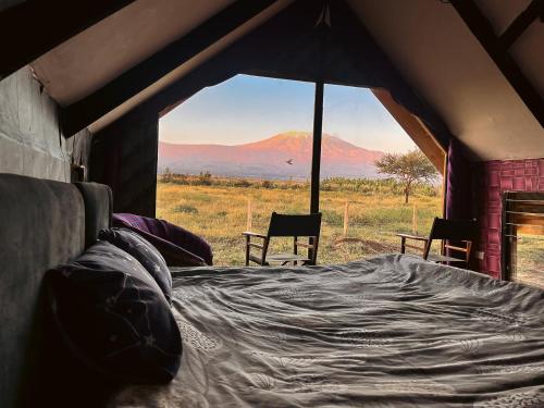 a bed in a tent with a view of a mountain at Kilimanjaro view cabin-Amboseli in Oloitokitok 