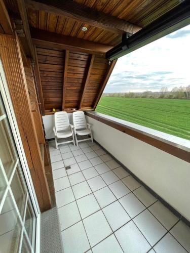 a balcony with two chairs and a view of a field at Großzügige Ferienwohnung für bis zu 4 Personen mit Balkon in Capelle