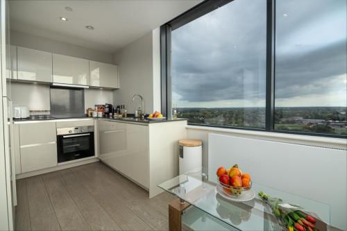 a kitchen with a glass table and a large window at Heathrow Family Apartments in Sunbury Common