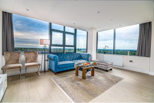a living room with a blue couch and large windows at Heathrow Family Apartments in Sunbury Common