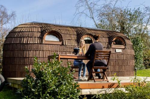 Un uomo e una donna seduti a un tavolo di fronte a una yurta di les Refuges du Chalet a Sart-lez-Spa