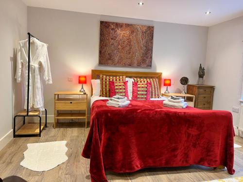 a bedroom with a red bed with a red blanket at 1-BedCottage ModrnKitchen CarCharging Tv Wifi in Coleford