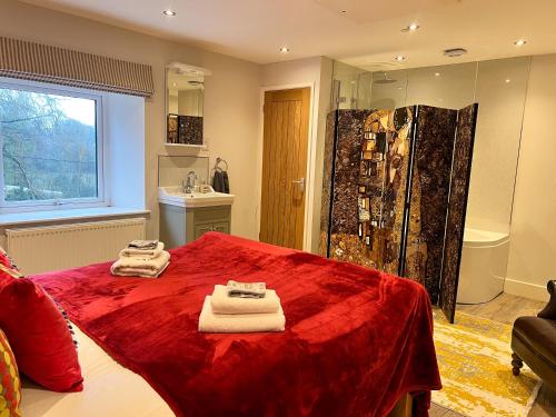 Wren is a stunning 1-Bed Cottage near Coleford في كول فورد: حمام به سرير احمر وعليه مناشف