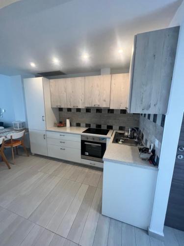 a kitchen with white cabinets and a stove top oven at Nea Peramos Apartment SeaFront in Néa Péramos