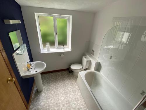 a bathroom with a tub and a toilet and a sink at Glenan Lodge Self Catering in Tomatin
