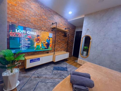 a living room with a tv and a brick wall at MIS HOSTEL Cần Thơ in Can Tho
