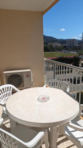 a white table and chairs on a balcony at studio avec coin nuit, 100 m de la mer in Le Lavandou