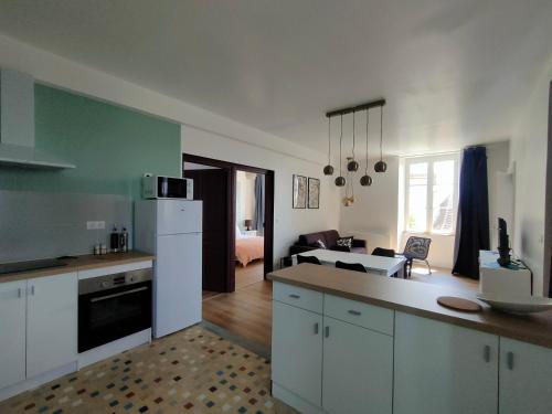 a kitchen with white cabinets and a living room at Les Epingliers - Le Clos Lacam, centre ville, dog friendly in Gourdon-en-quercy