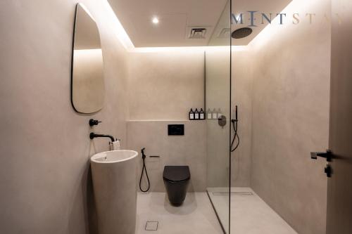 a bathroom with a sink and a toilet and a mirror at Sky Gardens, Park Avenue, DIFC - Mint Stay in Dubai