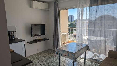 a room with a television and a table in front of a window at studio avec coin nuit, 100 m de la mer in Le Lavandou
