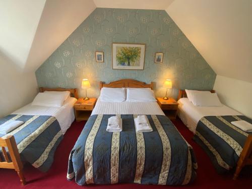 two beds in a hotel room with two lamps at Glenan Lodge Self Catering in Tomatin