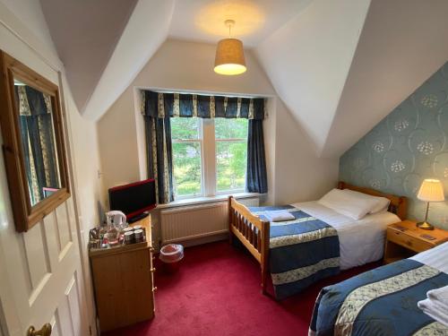 a small bedroom with two beds and a window at Glenan Lodge Self Catering in Tomatin