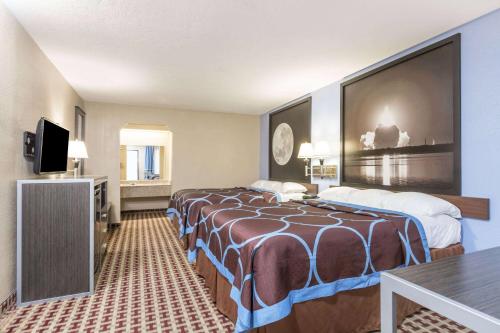 a hotel room with two beds and a flat screen tv at Super 8 by Wyndham Houston Webster NASA in Webster