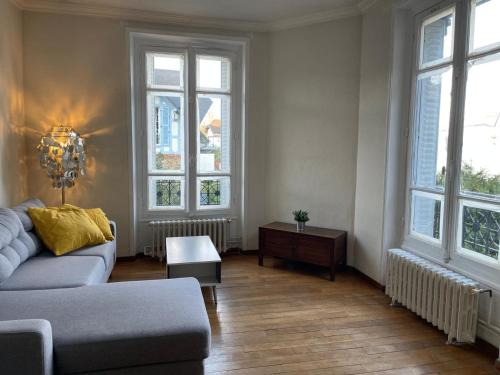 a living room with a couch and some windows at Cosy apartment in Paris area in Suresnes