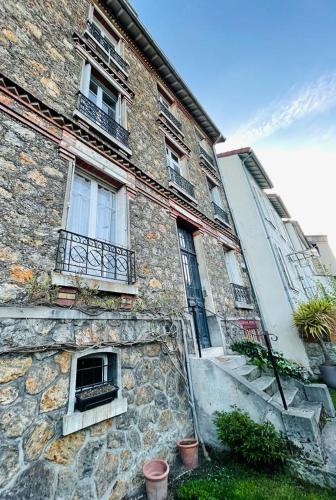 an old stone building with windows and a staircase at Cosy apartment in Paris area in Suresnes