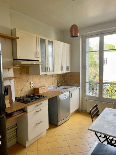 a kitchen with white cabinets and a stove top oven at Cosy apartment in Paris area in Suresnes