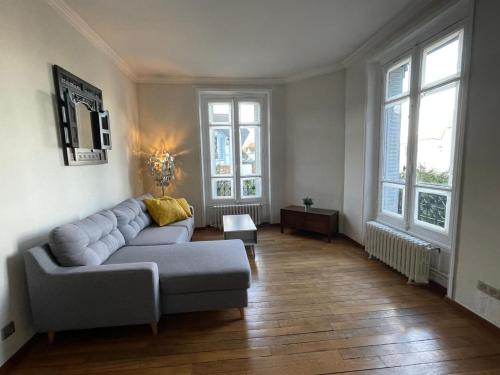 a living room with a couch and two windows at Cosy apartment in Paris area in Suresnes
