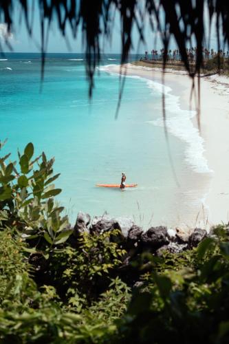 a person on a surfboard in the water on a beach at Bo'a Vida Rote in Nembrala