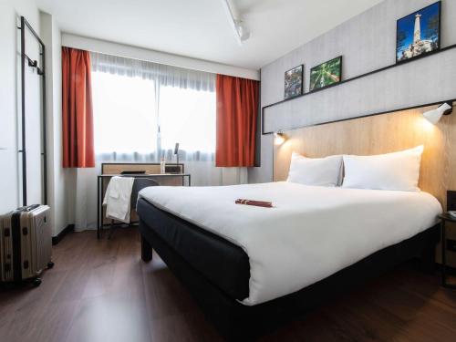 una camera d'albergo con un grande letto e una scrivania di ibis Paris Gare de Lyon Diderot a Parigi