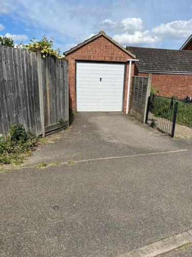 a garage with a white garage door and a fence at Family & Contractors Complementary Wine Coffee Tea in Earith
