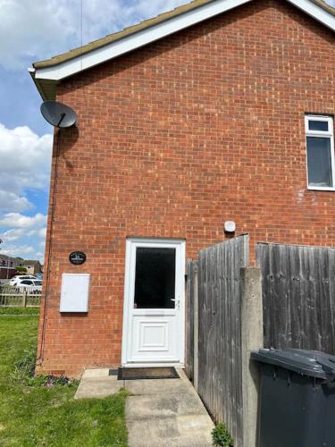 a brick house with a white door and a fence at Family & Contractors Complementary Wine Coffee Tea in Earith
