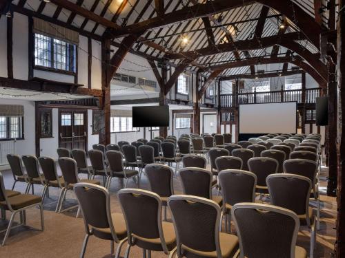 a room with rows of chairs and a projection screen at Sunday Box Hill Burford Bridge Hotel in Dorking