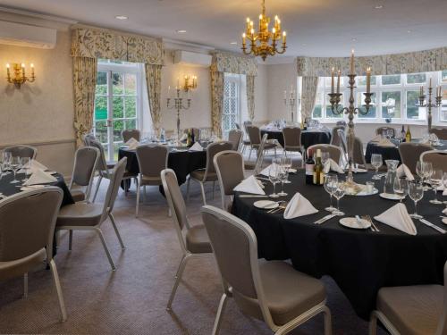a conference room with tables and chairs and a chandelier at Sunday Box Hill Burford Bridge Hotel in Dorking