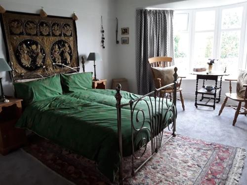 a bedroom with a bed with a green comforter at Halcyon Days in Kenwyn