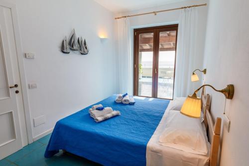 Un dormitorio con una cama azul con toallas. en Villa Tre Mari en Villasimius