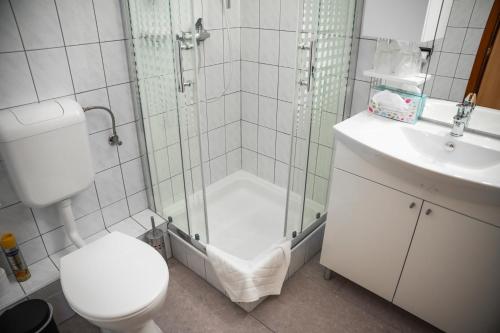 a bathroom with a shower and a toilet and a sink at Hotel Bolero in Győr