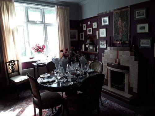 a dining room with a table and a fireplace at Halcyon Days in Kenwyn