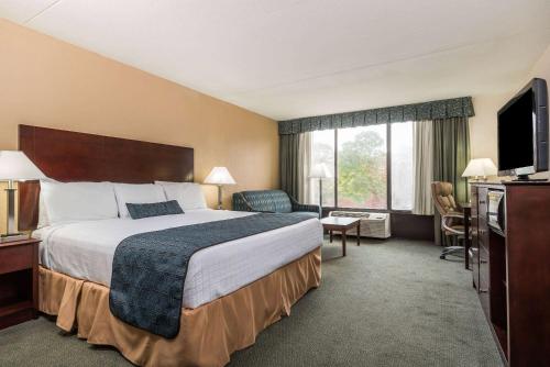 Habitación de hotel con cama grande y TV en Wyndham Garden Williamsburg Busch Gardens Area, en Williamsburg