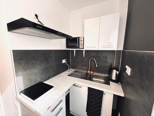 a small kitchen with white cabinets and a sink at Keli Apartments Zentrum Oldenburg in Oldenburg