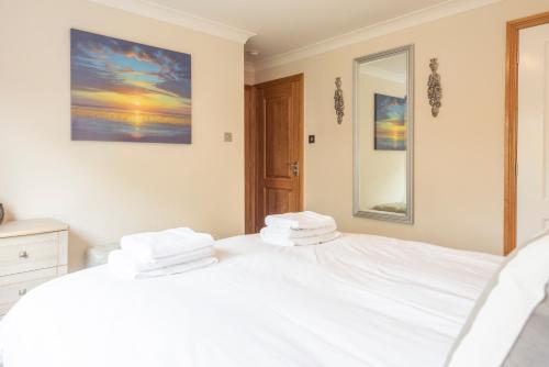 a bedroom with a bed with white sheets and a mirror at 5 Toller Close, Orford in Orford